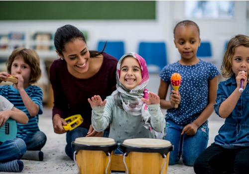 An instructor showing a child how to play drums in a Peoria IL daycare