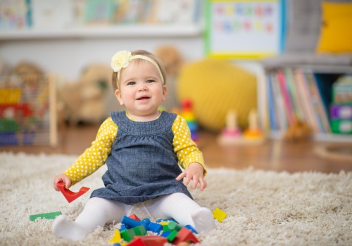 A baby plays with blocks and smiles at PALS, the Best Infant Care in Peoria County IL