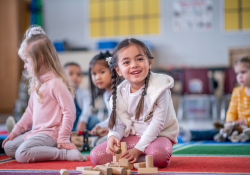 A toddler smiles while building with blocks at PALS, which offers the best Pre-K Near You