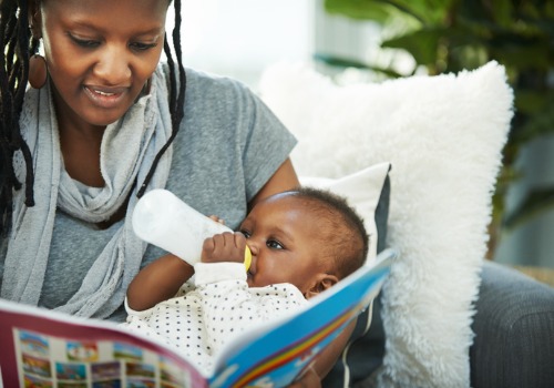 A mother reads to her infant, which is a great way to reach Developmental milestones for a baby