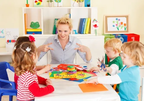 A teacher at PALS, which is one of the top Preschools Near Metamora IL, shows kids how to cut using her fingers.