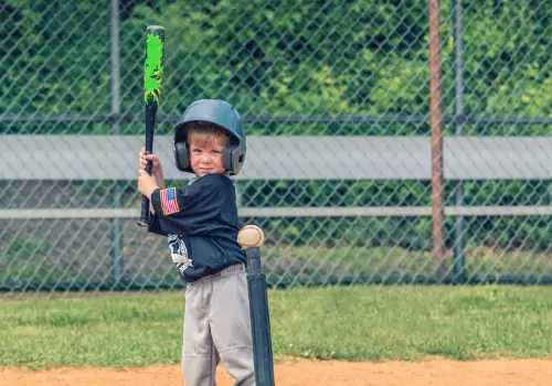 A little boy starts to swing at a ball on a t-ball, which is one of the best Sports for Developing Hand Eye Coordination