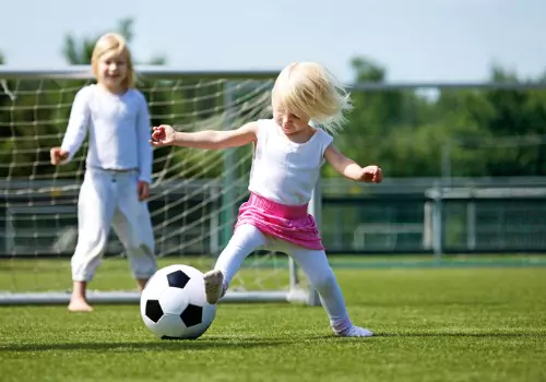 A little girl kicks a soccer ball, which is one of the best Sports for Developing Hand Eye Coordination in toddlers and kids