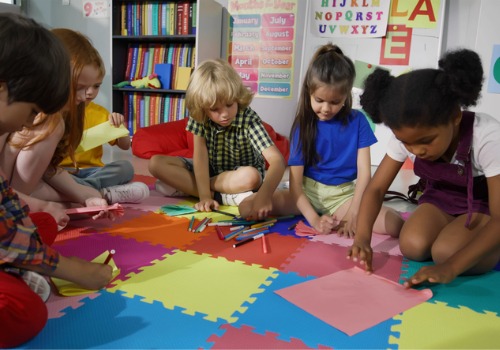 A group of preschool children sit in a circle and draw. Social Interaction is Important for Kids as they grow into adulthood.