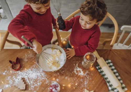 Toddlers stir ingredients for Christmas cookies. Teaching moderation is one of the great ways you can practice Keeping Kids Healthy During the Holidays.